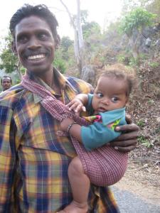 Father carries baby in sling while walking home from the market in rural Orissa.